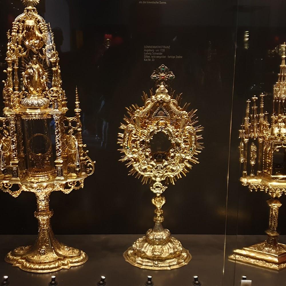 Three golden monstrances in a museum display.